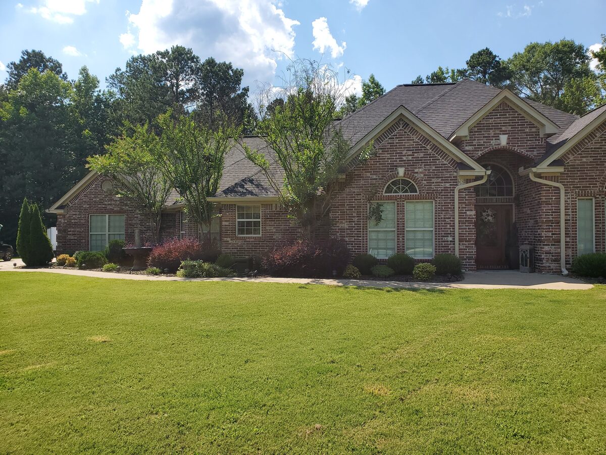 Upscale brick residence with manicured lawn and mature foundation plantings